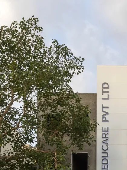 The new facade of Educare Pvt Ltd, seen alongside a mature tree, illustrates how our contemporary designs can coexist with and complement the natural environment.