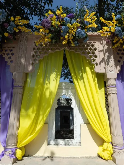A decorated archway with bright yellow drapes and floral toppers, framing a window of the palace. This shows how we use decor to complement existing architecture.