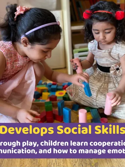 Two girls playing together with wooden blocks. Through cooperative play, children learn essential social skills like sharing, communication, and taking turns.