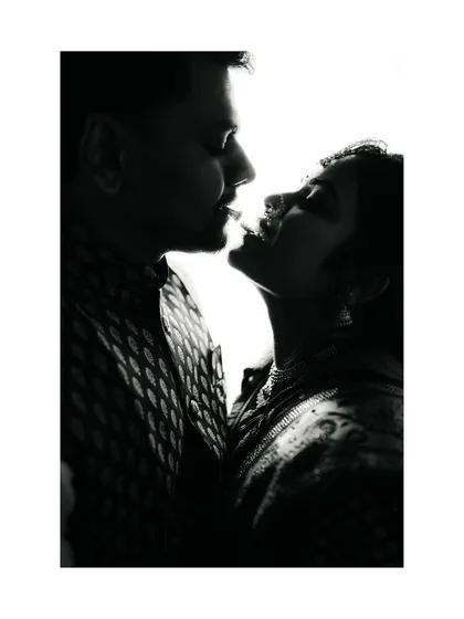 A high-contrast, silhouette-style black and white portrait. This artistic shot focuses on the couple's profiles and the space between them, creating a dramatic and intimate mood.