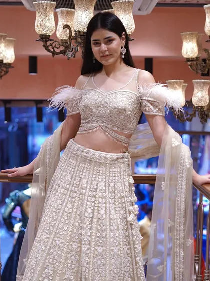Drape yourself in opulence with this gold and white lehenga, complete with stunning feather sleeve detailing.