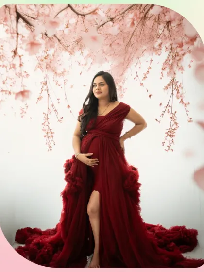 A dreamy and artistic portrait with a floral canopy. The expecting mother in a deep red gown looks absolutely ethereal in this beautifully styled studio shot.