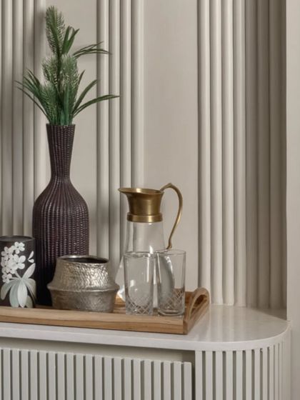 Details matter. A simple tray with a water jug and decorative items on the console adds a touch of hospitality and style to this neutral-toned bedroom.