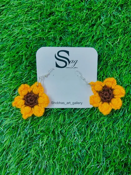 A pair of my cheerful sunflower crochet earrings. These handmade floral earrings are crafted with bright yellow and brown yarn, perfect for adding a touch of sunshine to your day.