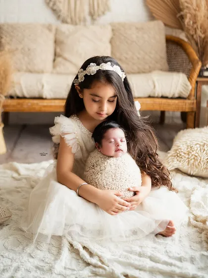 A big sister carefully holding her new baby sibling, a beautiful moment of new responsibility and love.