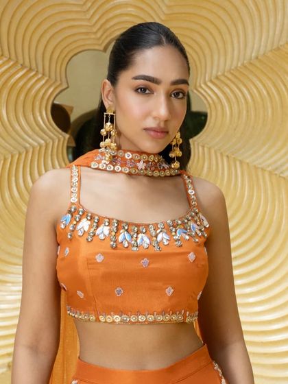 A close-up of the orange palazzo set, focusing on the stunning mirror and beadwork around the neckline of the blouse.