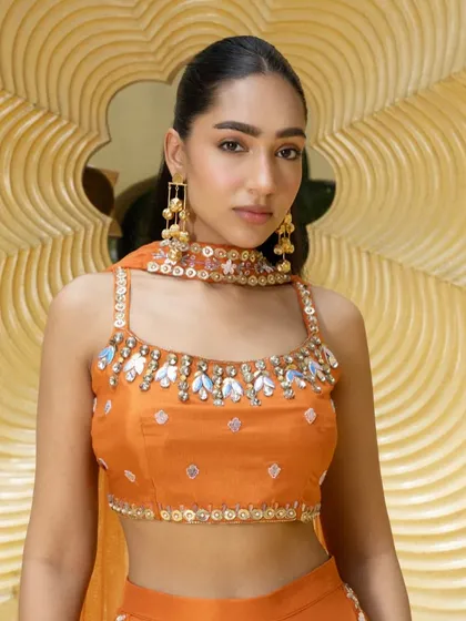A close-up of the orange palazzo set, focusing on the stunning mirror and beadwork around the neckline of the blouse.