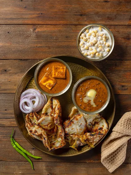 A North Indian thali featuring Chur-Chur Naan, Dal Makhani, and Shahi Paneer for Grover Sweets. The top-down composition on a wooden background creates a wholesome, rustic look.