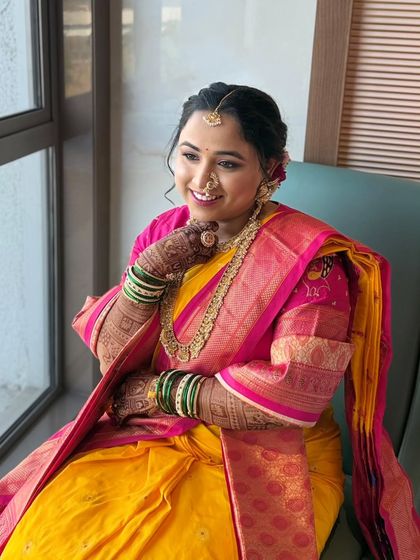 A candid shot of a happy bride in her stunning yellow and pink Nauvari saree. The makeup was crafted to be light and breathable, perfect for a long day of ceremonies, ensuring she felt as good as she looked.