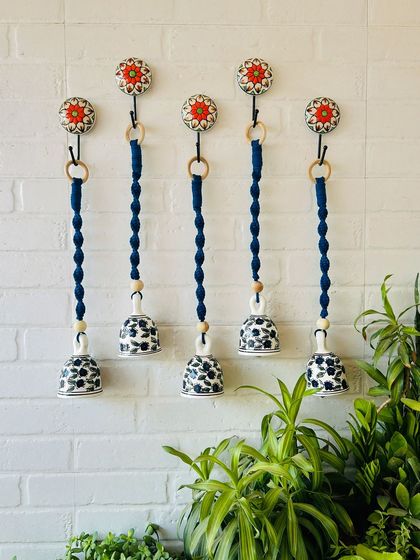 A set of five 'Sapphire' macrame ceramic bells in a deep blue color. These handcrafted pieces are perfect for adding a touch of elegance and serenity to your living room, patio, or garden.
