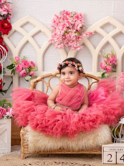 A royal portrait. Seated on her wicker throne amidst a sea of pink flowers, this little girl is the queen of her castle.