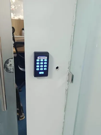 This is an RFID and password reader installed next to a glass door. It offers a keyless entry solution for employees using a card or a PIN code.