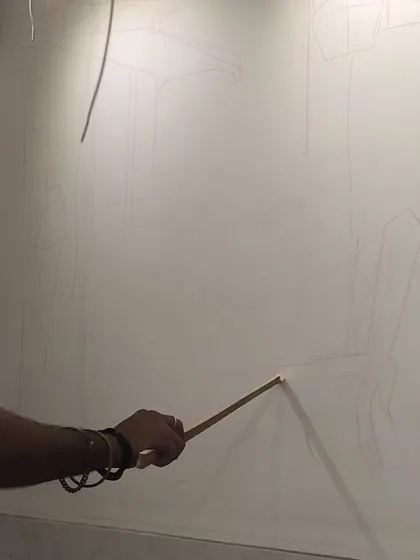 A close-up showing my hand as I draw the initial fine lines for the composition directly onto the wall. Precision at this early stage ensures the final painting has a solid structural foundation.