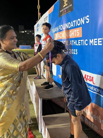 A young athlete receives her medal on the podium, a proud moment capping off the event.