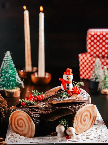 A classic Chocolate Yule Log (Bûche de Noël), decorated to look like a log from a winter forest. Complete with a tiny snowman and meringue mushrooms, it's a traditional centerpiece for your Christmas table.