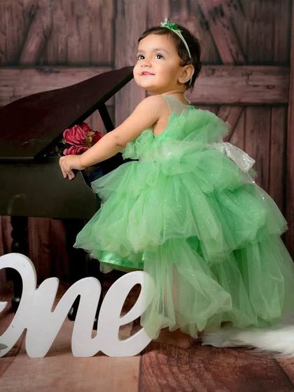 An elegant and classic first birthday portrait. This little girl looks so beautiful in her green dress, posing gracefully by the miniature piano.