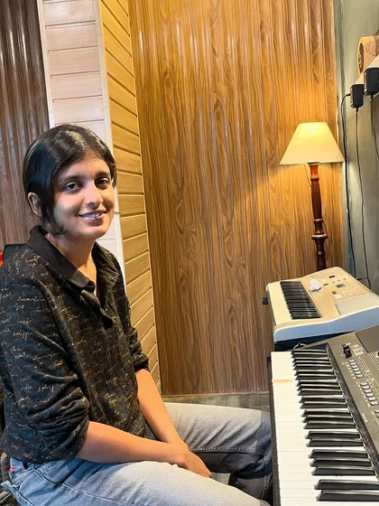 A smiling student sits at the keyboard, ready for her lesson. We offer both online and offline classes at our HSR Layout and Kaggadasapura locations.