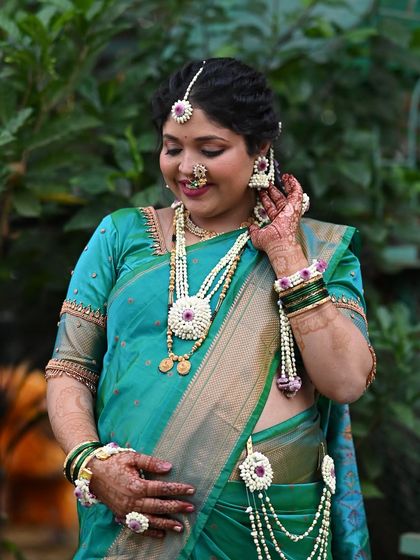 Adjusting the final touches. Every piece of floral jewelry, from the earrings to the armlets, is carefully placed to create a cohesive and beautiful look.