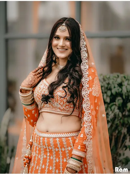 A radiant portrait of the bride on her engagement day. Her bright smile and beautiful orange lehenga light up the frame, capturing her happiness and excitement.