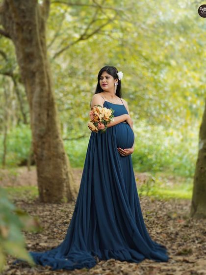 Standing amidst the trees, this portrait captures a feeling of peace and connection with nature. The flowing blue gown complements the greens of the forest perfectly.