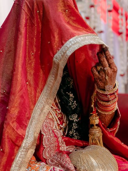 A portrait of the bride under her veil, with only her henna-decorated hand visible. This creates a sense of mystery and highlights traditional bridal elements.