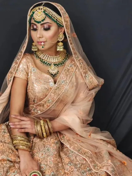 An elegant bride in a peach-colored lehenga with a matching green Kundan jewellery set. This soft and sophisticated look is perfect for a day wedding.