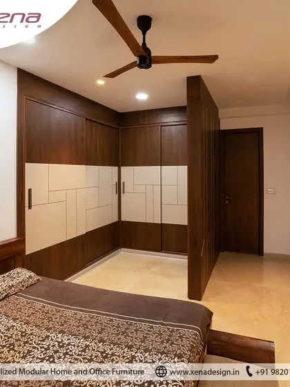 Here, we used a combination of dark wood laminate and white patterned shutters to create a striking L-shaped wardrobe. This design cleverly utilizes the corner space, providing ample storage while adding a strong visual element to the room.