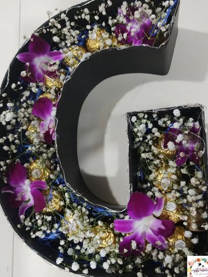 The alphabet bouquet without the lights on, showing the rich colors of the purple orchids and the delicate arrangement of the flowers and chocolates.