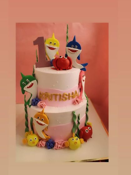 A two-tier Baby Shark cake for a first birthday. This 3kg cake is adorned with the entire shark family, made from detailed fondant work.