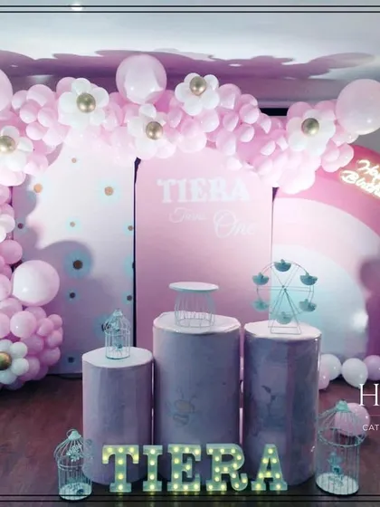 A slightly different angle of the pink-themed first birthday party. The lighting highlights the neon "Happy Birthday" sign and the intricate details of the balloon decorations.