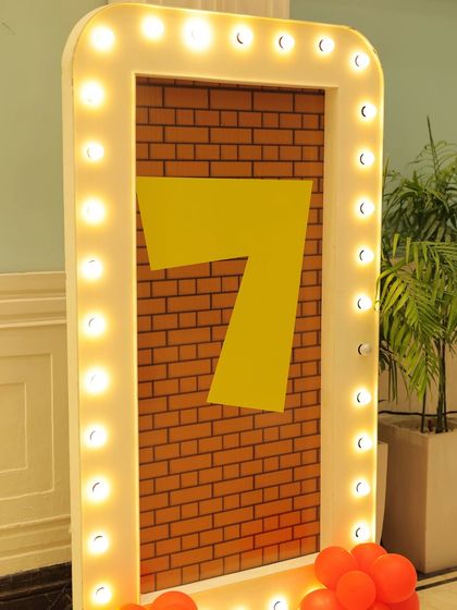 A light-up number '7' sign with a brick background, perfect for a Super Mario fan's birthday. The marquee lights add a touch of spectacle to the decor.