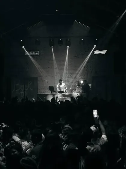 A black and white view of the entire club from the back. The spotlights on the stage create a dramatic focal point.
