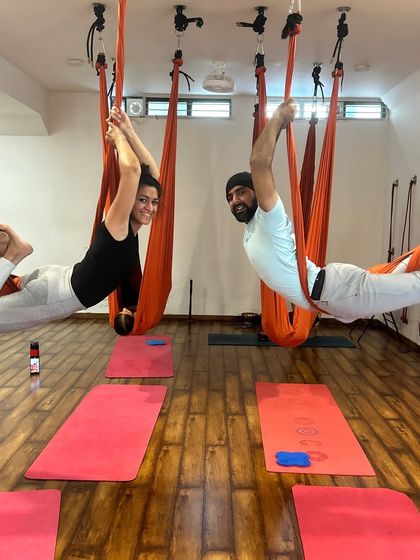 A couple enjoying an aerial yoga session together. It's a fun way to connect and support each other's fitness journey.