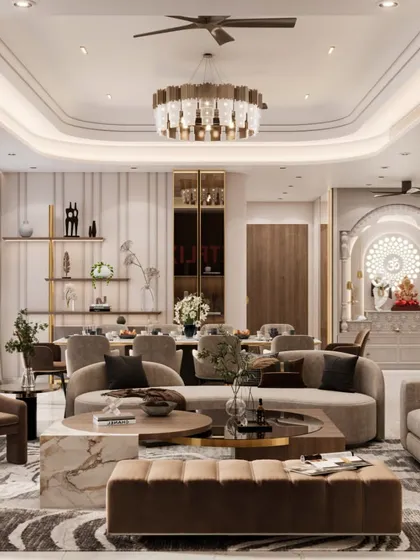 This contemporary living room design combines warm, earthy tones with luxurious comfort. The space features a custom-designed pooja mandir, a statement chandelier over the dining area, and plush, curved sofas, all working together to create a sophisticated and welcoming family space.