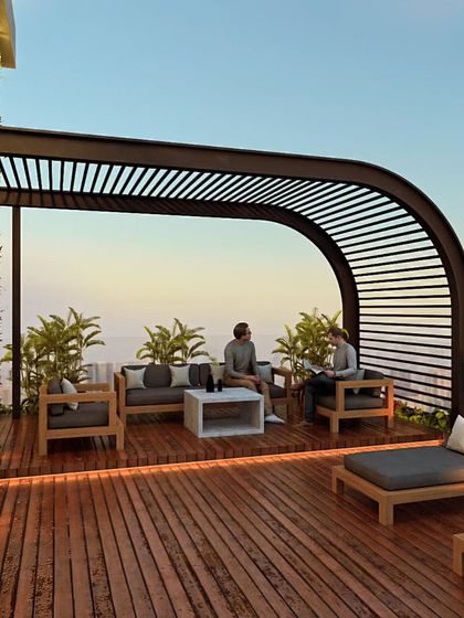 The rooftop terrace of Haresh Bhuvan, featuring a shaded lounge area. This space is designed for relaxation and socializing, with a vertical garden wall and comfortable seating that overlooks the city.