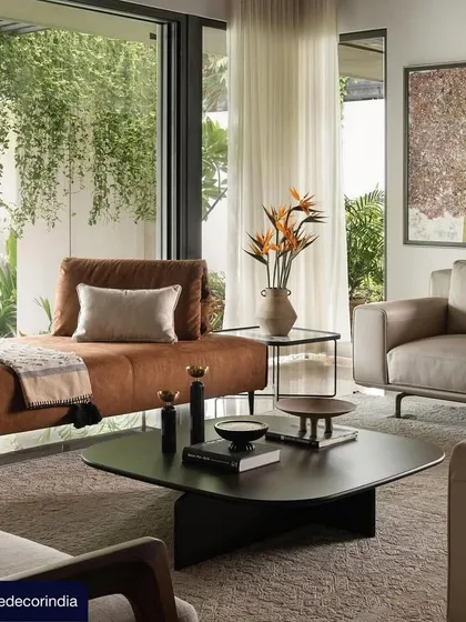 An image from the Elle Decor feature on Villa Shakthi, showcasing the living area's seamless connection to the lush green outdoors. The design uses a mix of contemporary furniture and natural light to create a serene and inviting space.