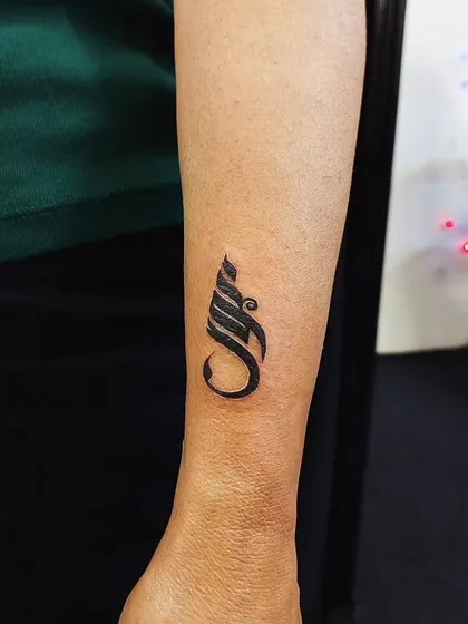 A bold, abstract calligraphic symbol on the forearm. This type of design is perfect for creating a unique and personal statement piece.