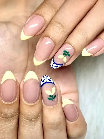 When life gives you lemons, get them on your nails. A juicy twist on French tips with pastel yellow, leafy green sprigs, and a ceramic tile-inspired accent nail.
