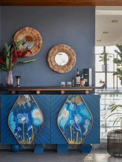 A bespoke home bar cabinet designed as a piece of functional art. The deep blue chevron-patterned wood is inlaid with hand-painted panels, creating a unique statement piece for entertaining. This detail highlights our expertise in custom furniture design and using bold colors to add personality to a space.