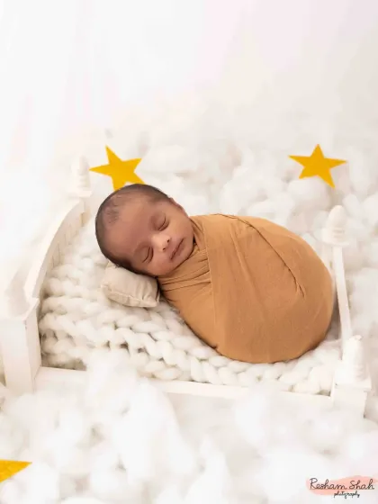 Dreaming among the clouds and stars. This whimsical setup with a tiny bed, fluffy clouds, and golden stars creates a magical, celestial scene for a sleeping newborn.