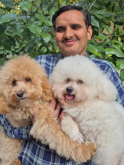 A close-up of our team member, Narain, with two of our fluffiest clients, Archie and Columbus. His gentle handling and clear affection for the dogs are representative of our entire team's attitude.