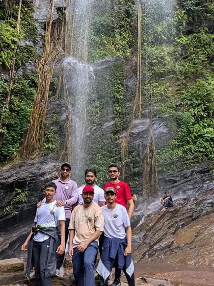 A group of friends posing in front of the beautiful, vine-covered rocks at Hidlumane Falls.