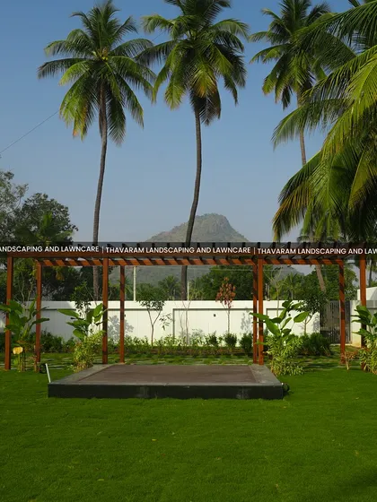 A view of the expansive lawn featuring a modern wooden pergola over a raised deck, set against a backdrop of palm trees and distant mountains.