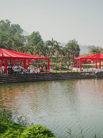 A wide shot of the lakeside venue, with two striking red canopies creating a festive and inviting atmosphere for the celebration.