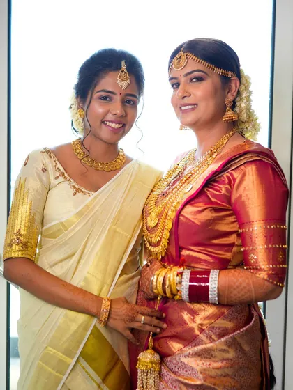 The bride with her sister, both looking elegant in their traditional sarees. The bride's makeup is soft and glowing, enhancing her features beautifully.