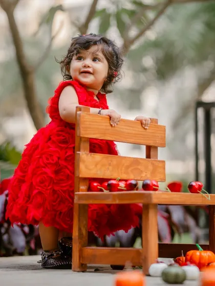A duplicate of image 4, this adorable baby girl in a vibrant red dress for her first birthday shoot. I use simple props like this small wooden chair to add charm without distracting from the star of the show.