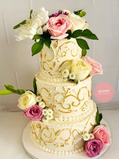 A luxurious 5 kg Belgian Chocolate cake with hazelnut crunch, designed as a show-stopping centerpiece. This three-tier beauty features intricate golden detailing and a cascade of fresh flowers.