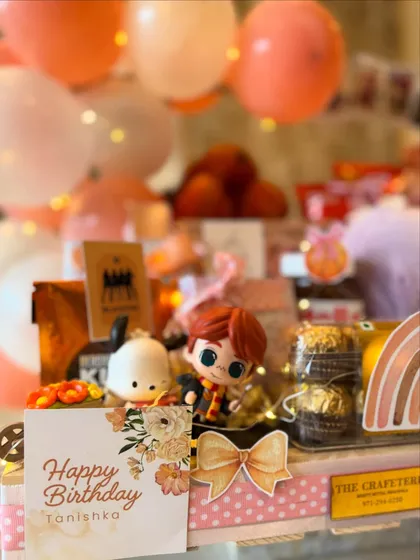 A close-up of the personalized 'Happy Birthday Tanishka' card, surrounded by whimsical figurines and treats. Every detail is designed to make a young girl's birthday feel truly magical.
