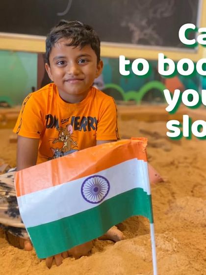A young boy holds the Indian flag while playing in the sandpit. We incorporate national pride into our everyday play during Independence Day celebrations.