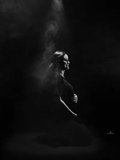 A low-key black and white portrait capturing a moment of quiet contemplation. The smoke rising from below adds a touch of mystery and drama to the scene.
